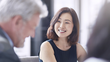 Glad kvinna i fokus, övriga mötesdeltagare suddiga