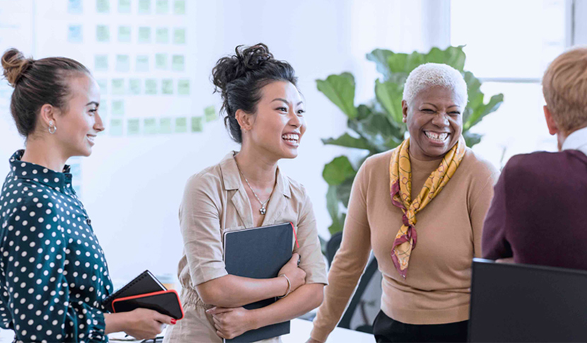 4 kvinnor talar och skrattar i kontorsmiljö