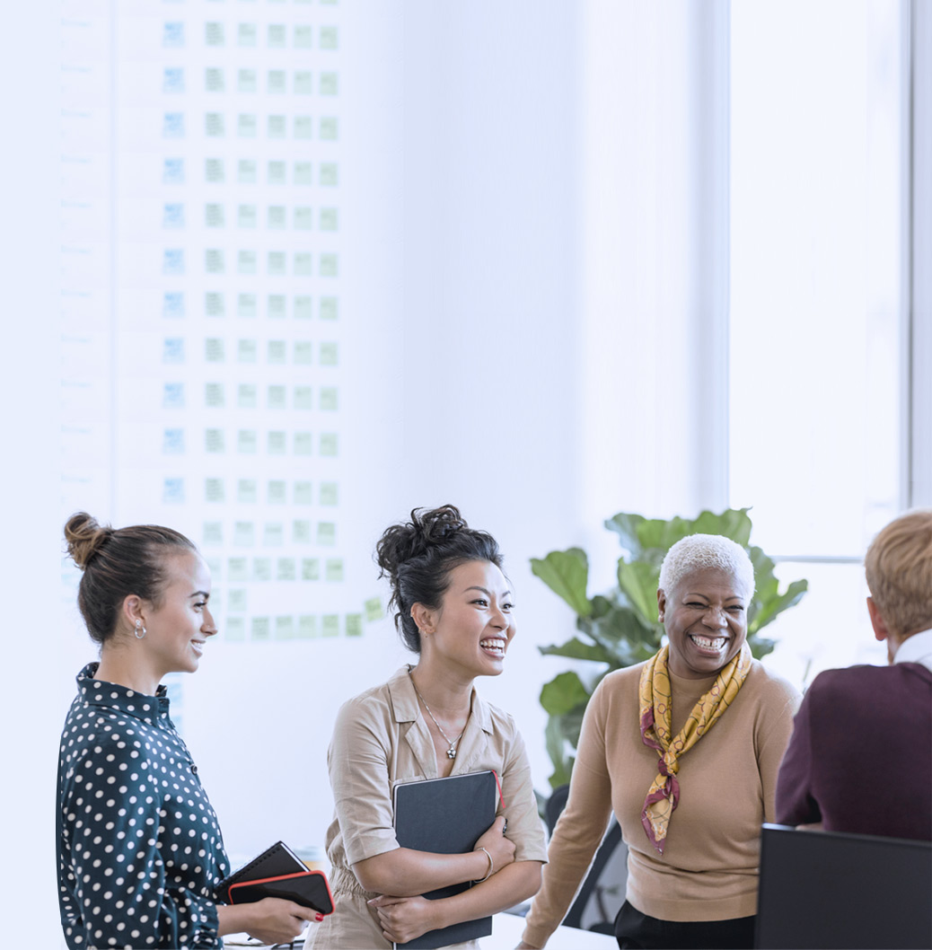 4 kvinnor talar och skrattar i kontorsmiljö